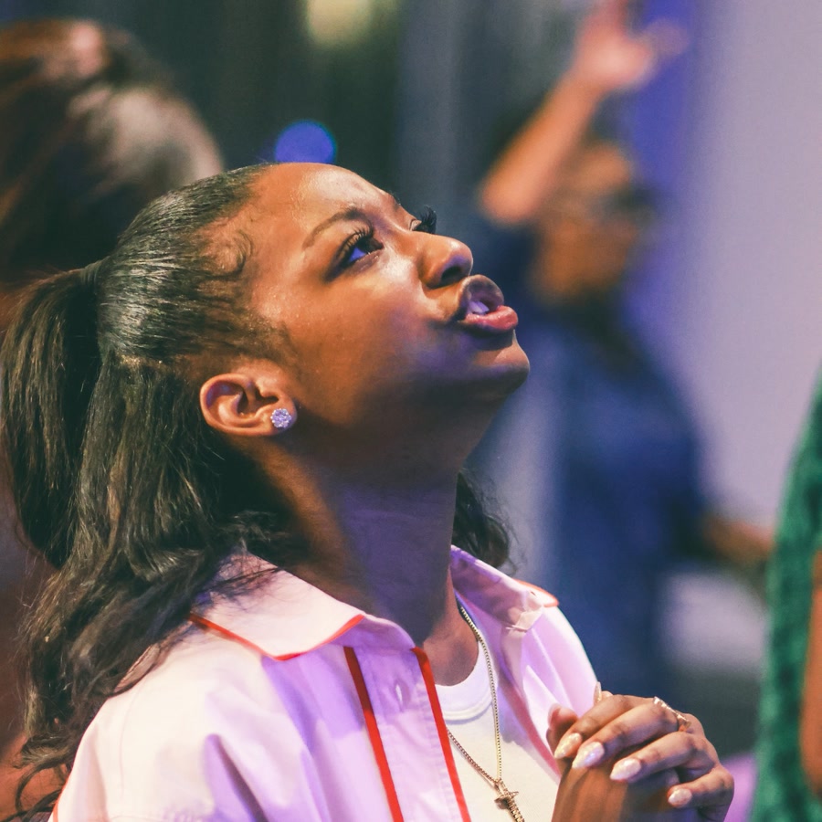 A young woman in prayer, hands clasped, eyes lifted